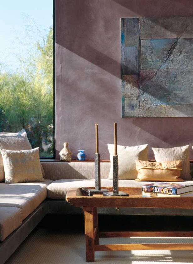 Vast expanses of floor-to-ceiling windows eliminate need for artificial light during daylight hours. Sunlight paints the walls of the great room, dramatic with its high ceilings and yet comfortable with its generous sofa, soft wool carpet, and rustic coffee table.